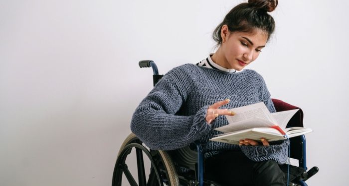 fair skinned woman in a wheelchair reading a books.jpg.optimal