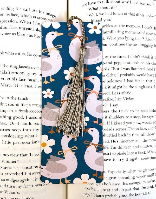 a goose-print bookmark with a grey tassel inside an open book