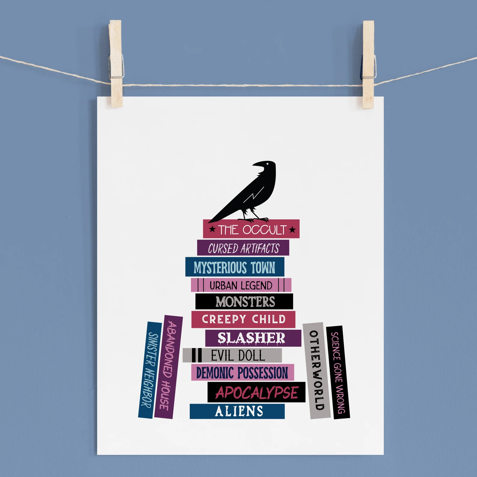 image of a print that has books with horror tropes on it and a raven on top of one of the book stacks. 