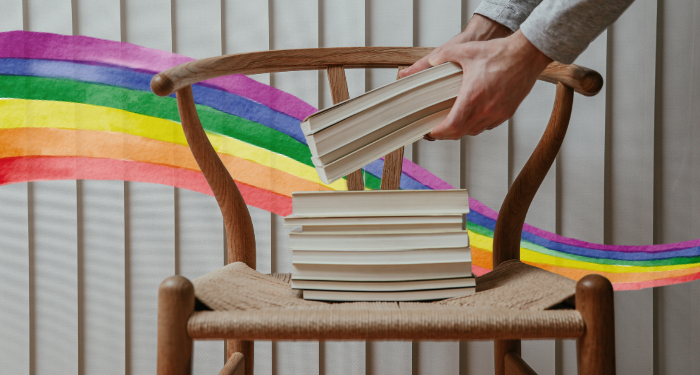 a stack of books with a rainbow watercolor ribbon in the background