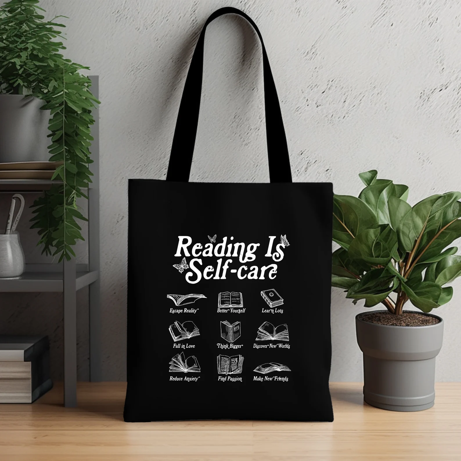 black tote bag with white text that reads "reading is self-care" and examples of how reading is self-care. 