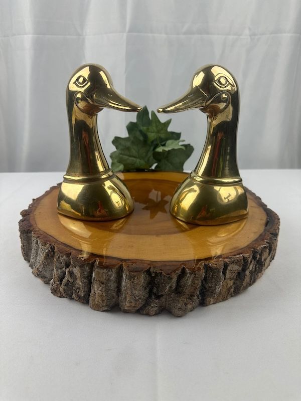 a pair of vintage brass duck head bookends resting on a woodcut