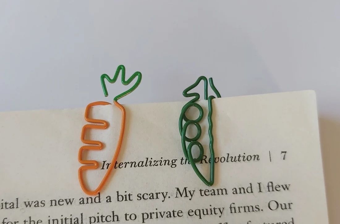 a photo of two paper clips, each one shaped like a carrot and a pea pod