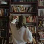 a woman in a hijab searching through shelves in a bookstore