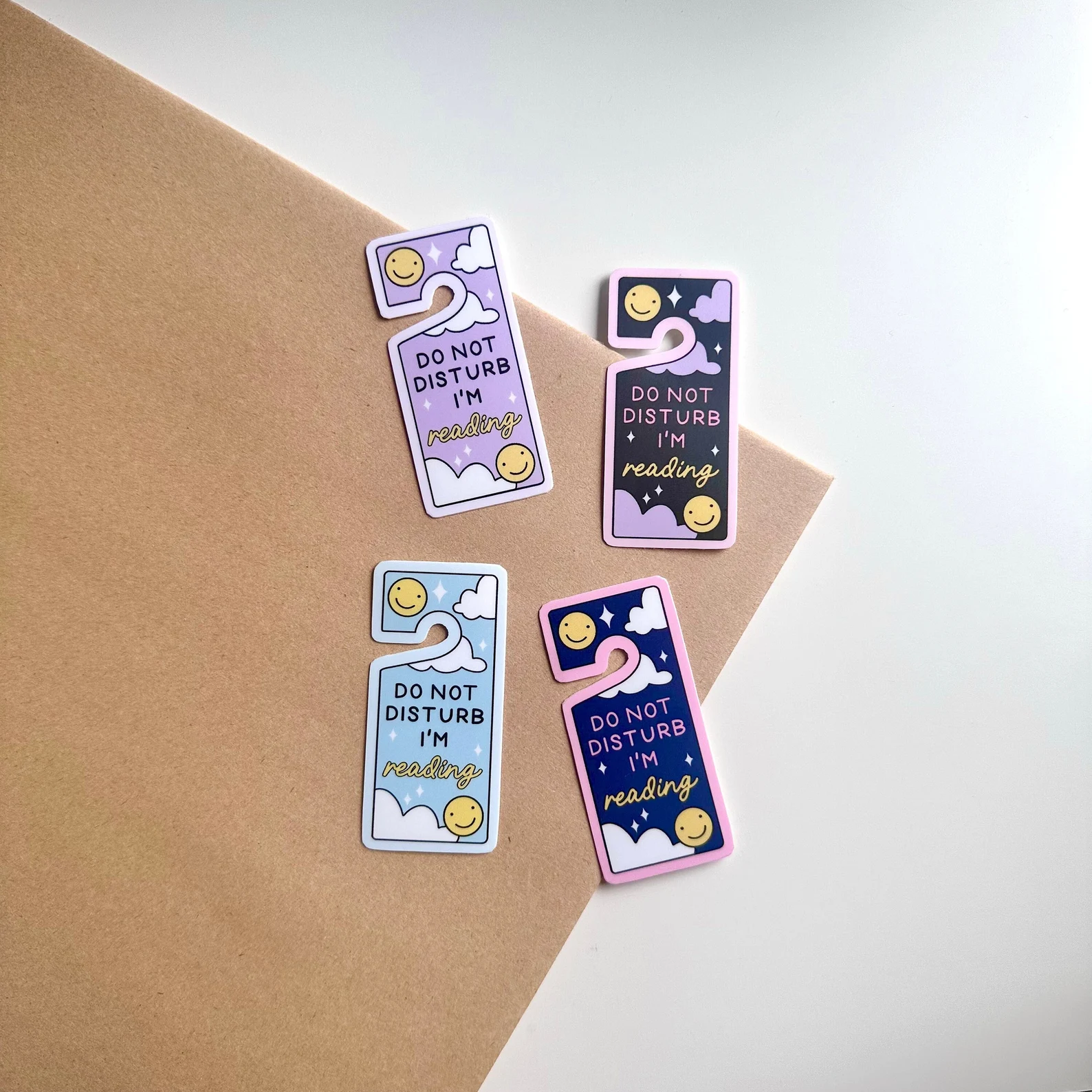 image of four stickers in the shape of door hangers. They are purple, blue, and black. They all read "do not disturb I'm reading."