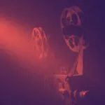 film reels on an old projector with a black and dark red filter applied to the image