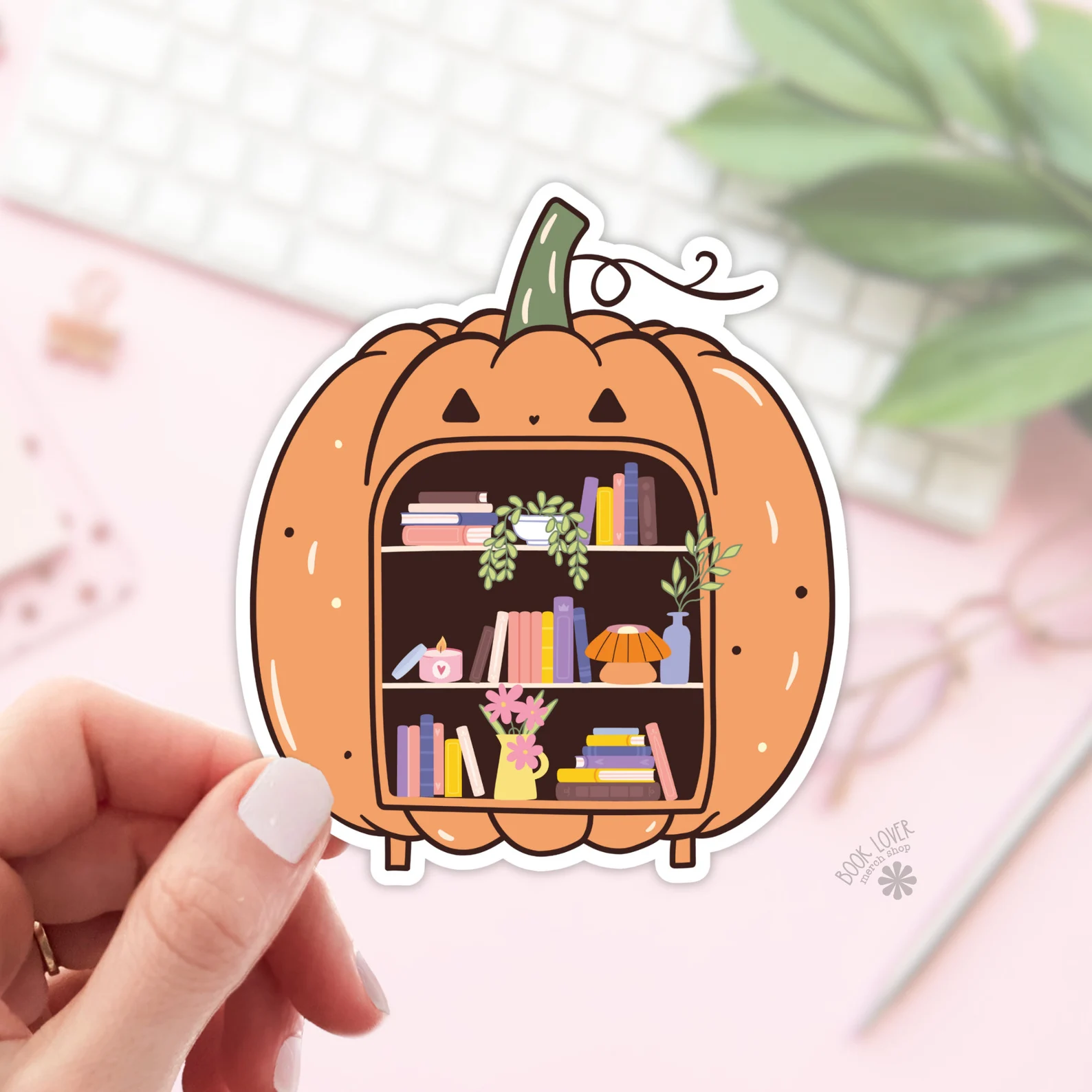 Image of a sticker that is a large pumpkin with books inside its mouth. 