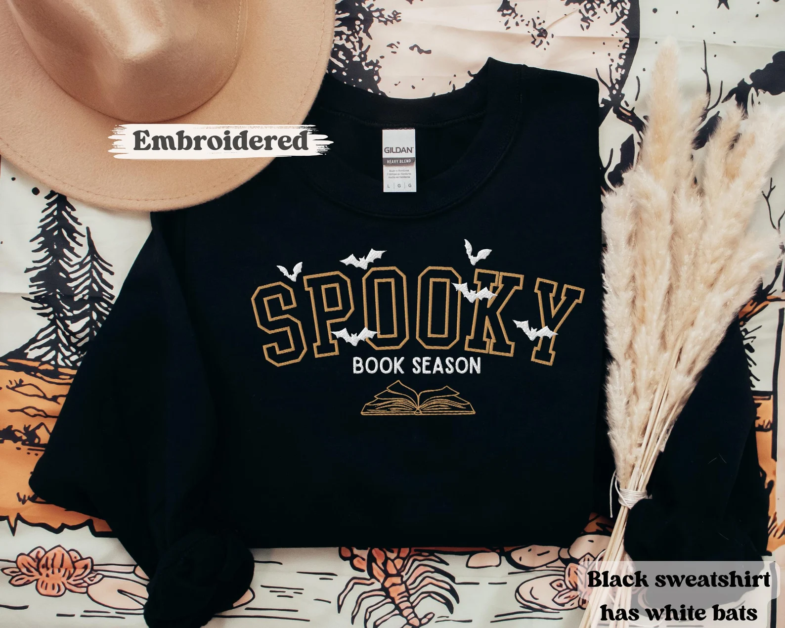 Image of a black crewneck sweatshirt. It says "spooky book season" in embroidery. 