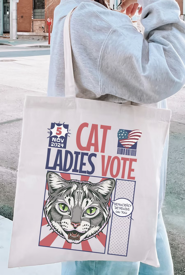 a tote bag with a graphic image of a cat's face and text saying "cat ladies vote"