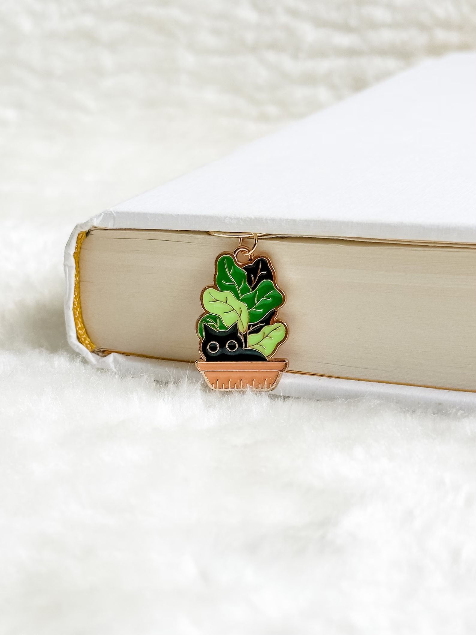 a photo of a book mark that features a black cat in a potted plant