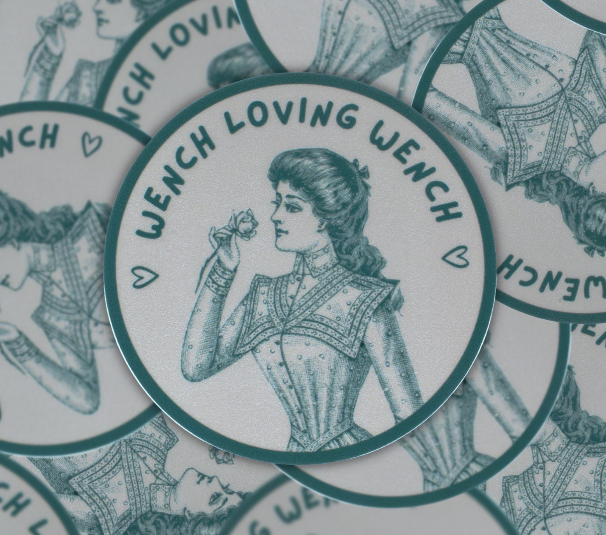 Image of a round sticker in white and blue with an illustration of a Victorian lady and the text "wench loving wench"