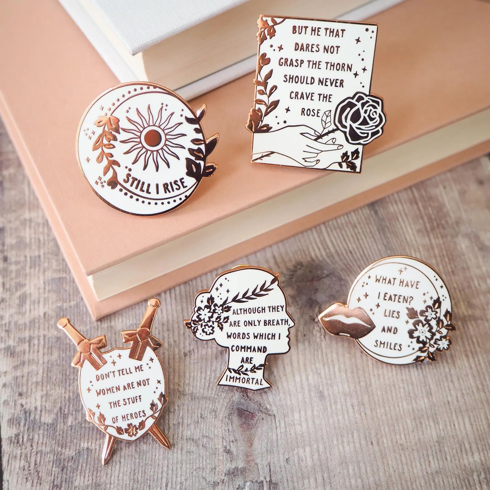 a photo of five enamel pins that feature quotes from women poets