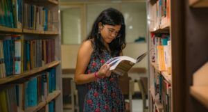 a tanned skin woman of color reading a book in a library