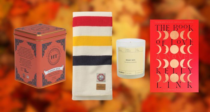 tea tin, wool blanket, candle, and BOOK OF LOVE book cover against blurred backdrop of autumn leaves