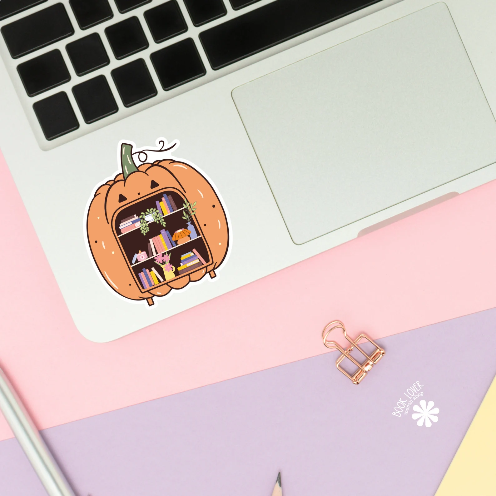 Image of a sticker on a laptop. The sticker is a pumpkin but instead of having a face, it has bookshelves. 