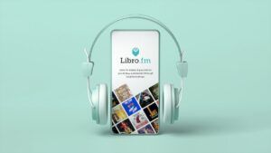 Teal background. Teal smartphone - on the screen of the phone shows the Libro.fm logo above the name, Libro.fm. Underneath "Libro.fm makes it possible for you to buy audiobooks through local bookshops" A pair of teal headphones surround the smartphone