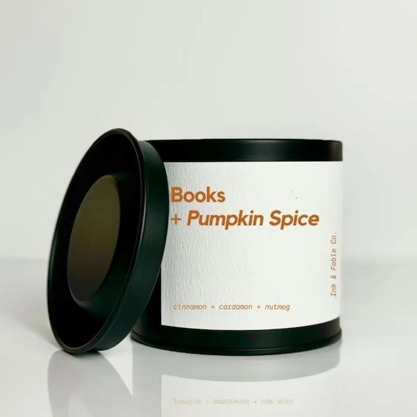 black candle with a cream label with orange text that reads Booms + Pumpkin Spice