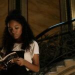 brown-skinned Black woman reading in a stariway