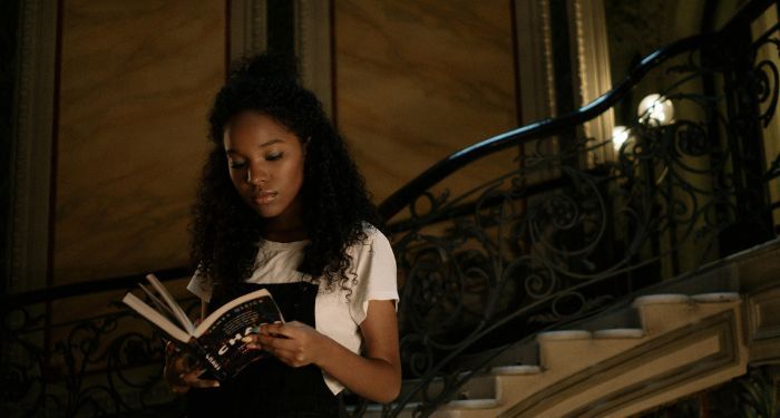 brown-skinned Black woman reading in a stariway