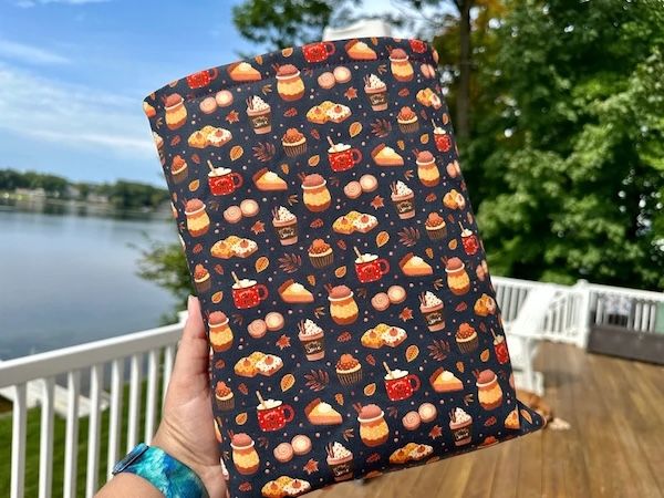 book sleeve in a pattern with tiny images of leaves coffee mugs, pumpkin pie slices, and baked goods, on a black background