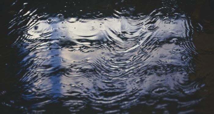 puddle of water on dark surface with light reflection