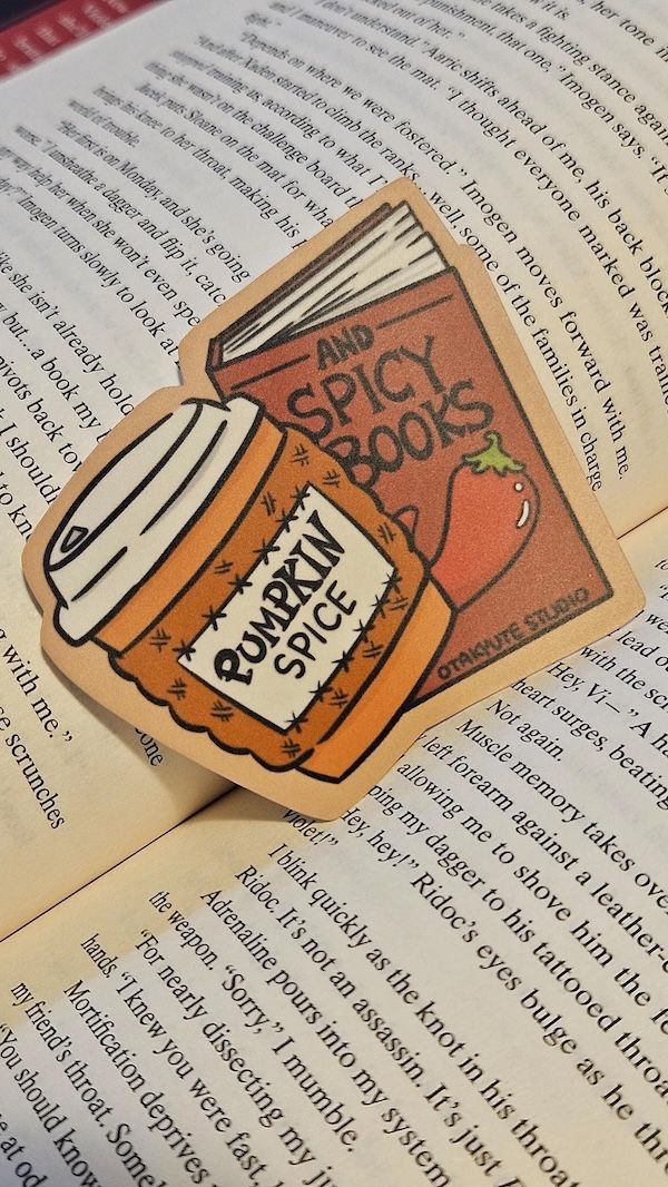 sticker of a paper coffee cup with a sleeve that says Pumpkin Spice and a book with the text And Spicy Books on the cover