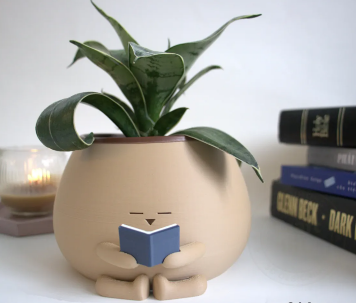 A ceramic pot reading a little book