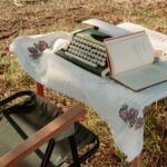 cover of a typewriter and a book on a table outside