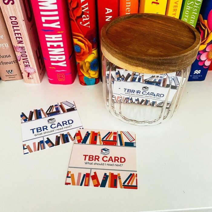 image of a jar full of scratch cards that say TBR Card, with two laying on the counter next to the jar 