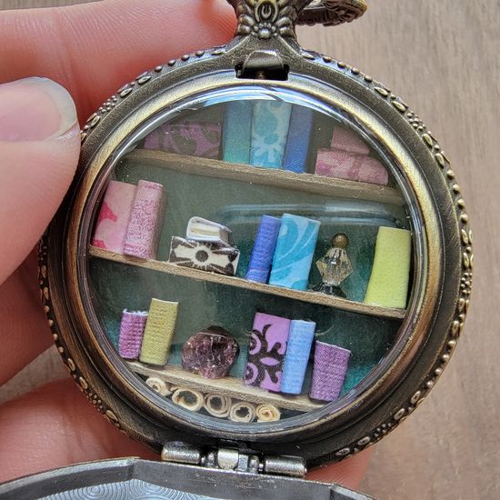 A miniature library in an antique gold toned pocket watch case.