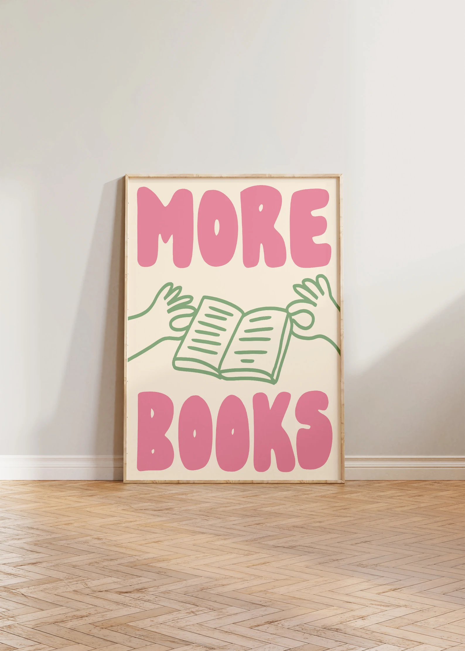 image of a vintage style print that says "more books" in pink. It has a green image of two hands holding an open book between the words "more" and "books."