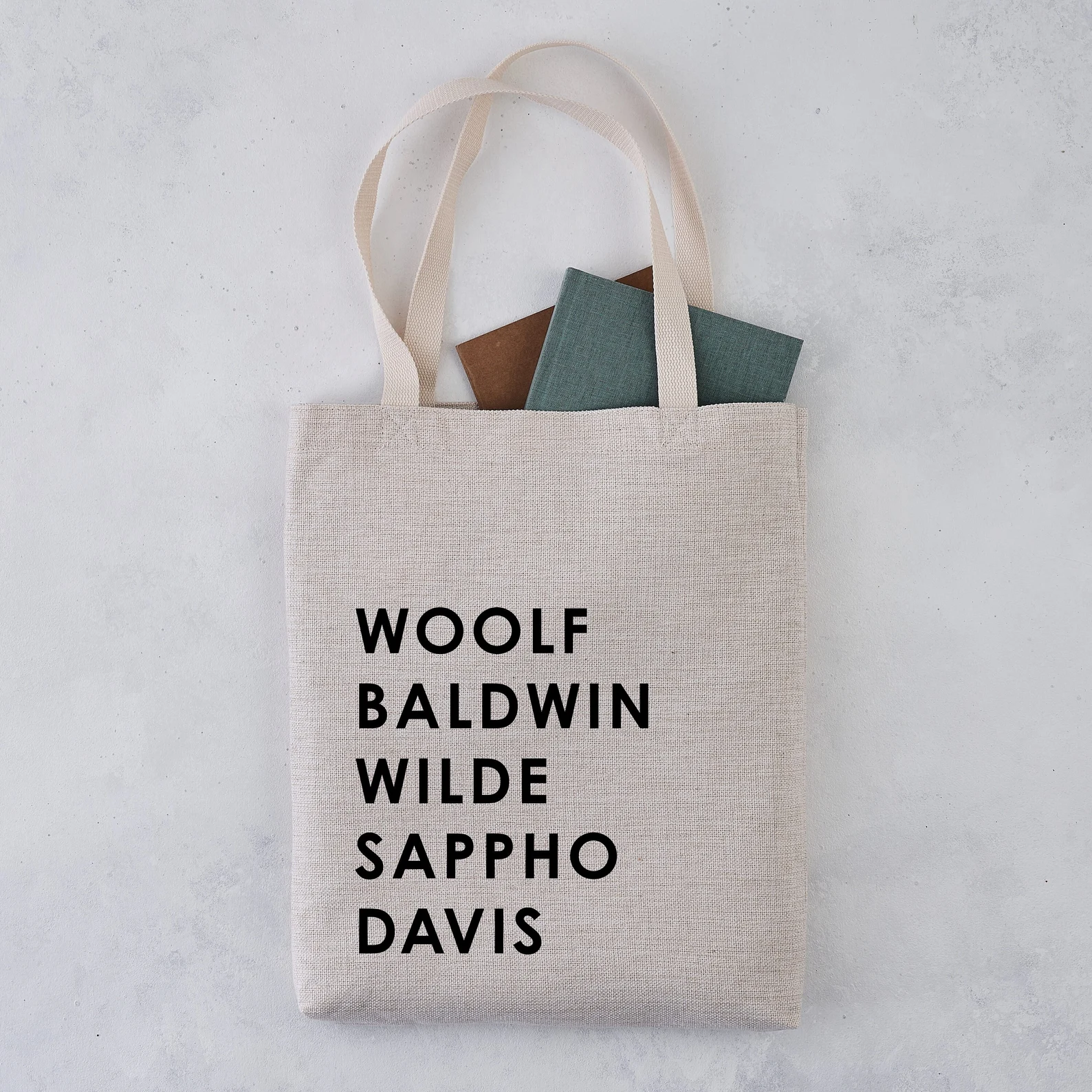 Canvas tote bag with the names of queer authors in black font. 