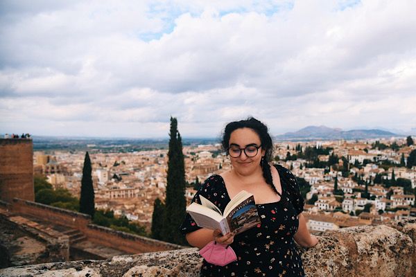 Woman reading book on a rooftop overlooking the city of Granada, Spain