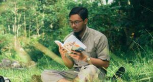 tan-skinned Asian man reading a book while sitting outside