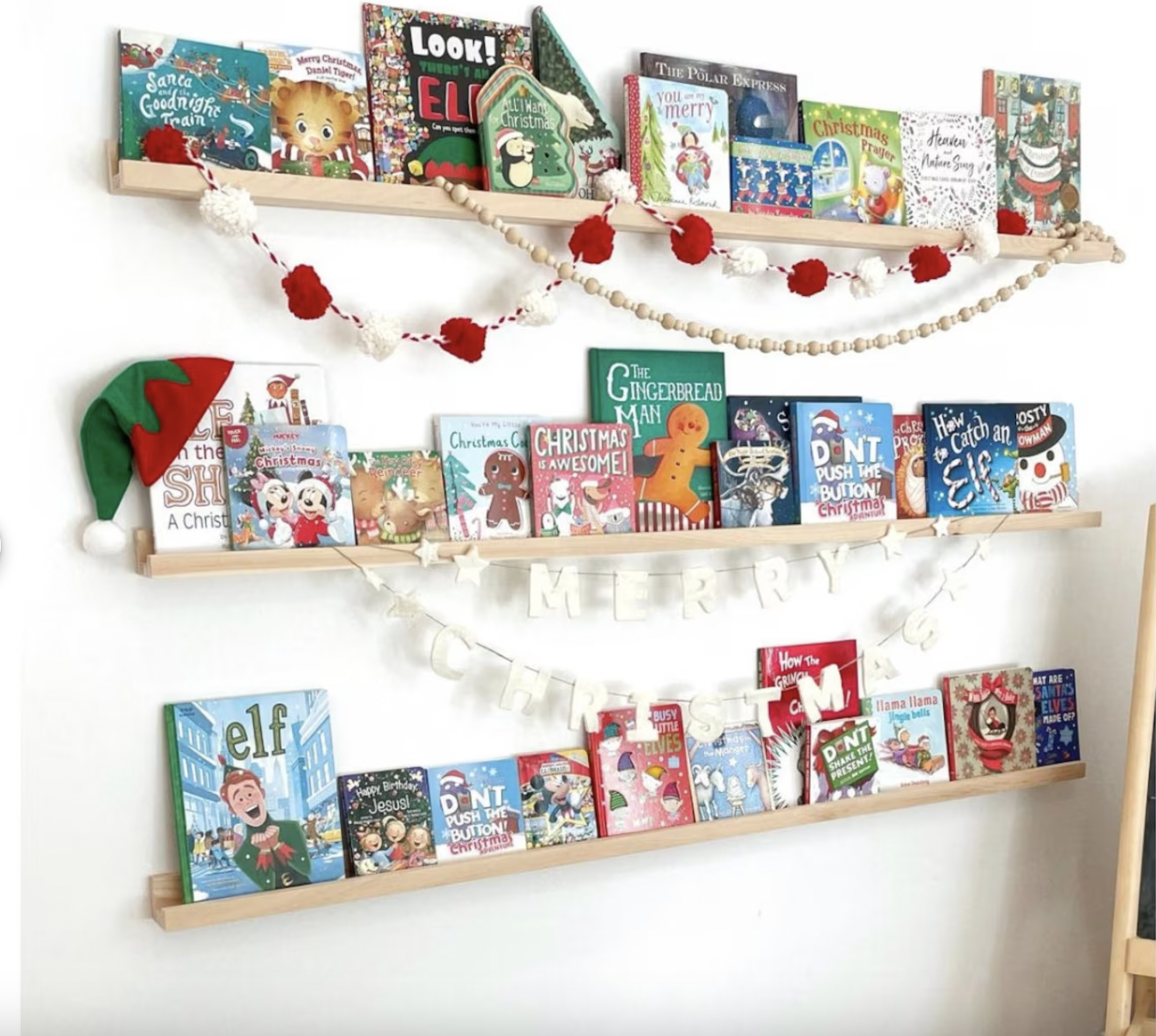 Photo of three slim wooden ledges on a wall displaying face-out children's books, decorated with streamers