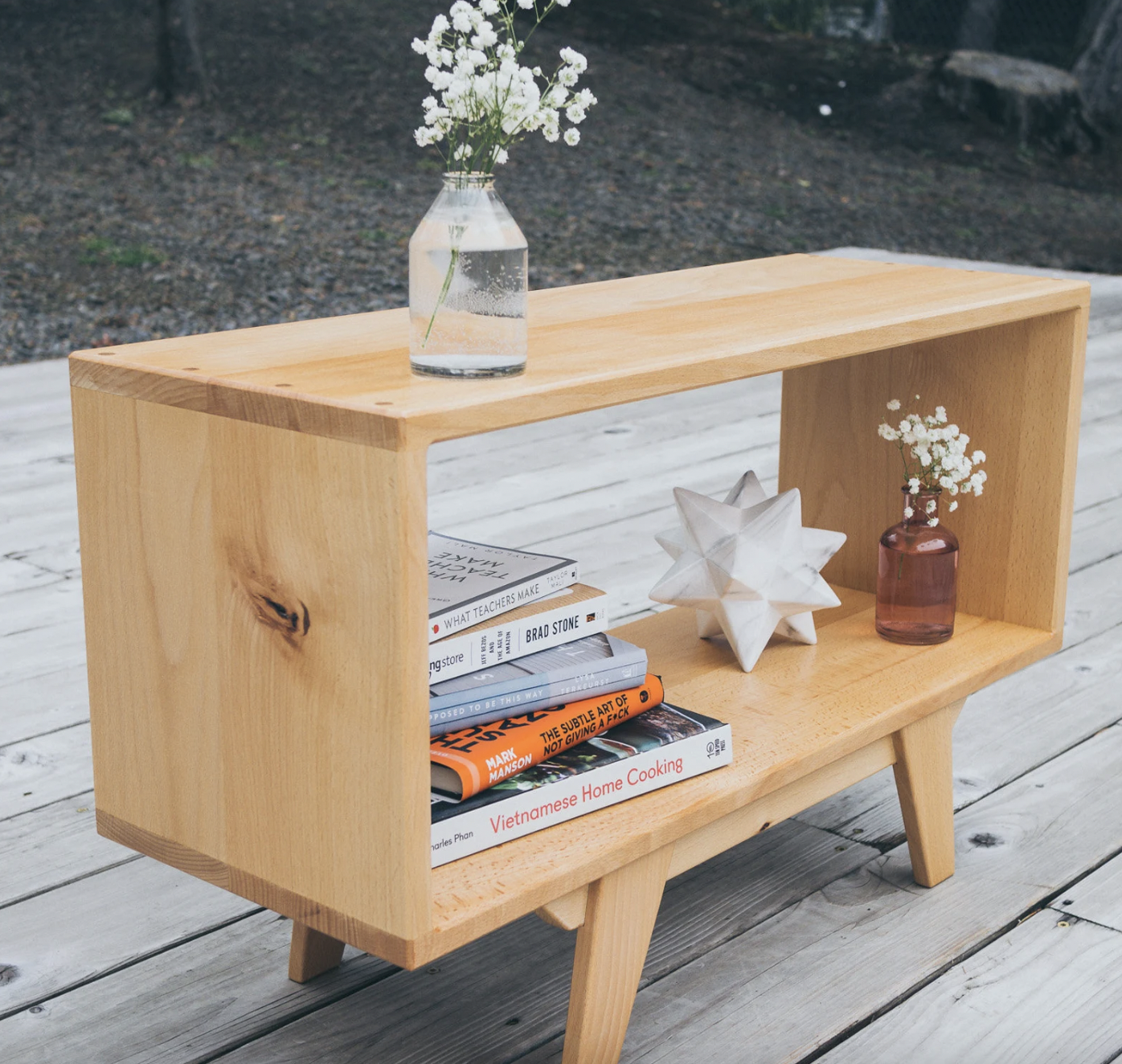 Photo of a wooden coffee table on short legs with an open shelf underneath holding books