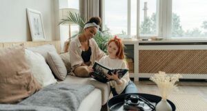 a brown-skinned Black woman and a fair-skinned white woman sitting and reading a book together