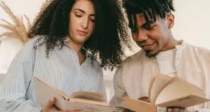 cover of a lighter-skinned woman with curly hair and a brown-skinned man with locs reading books together
