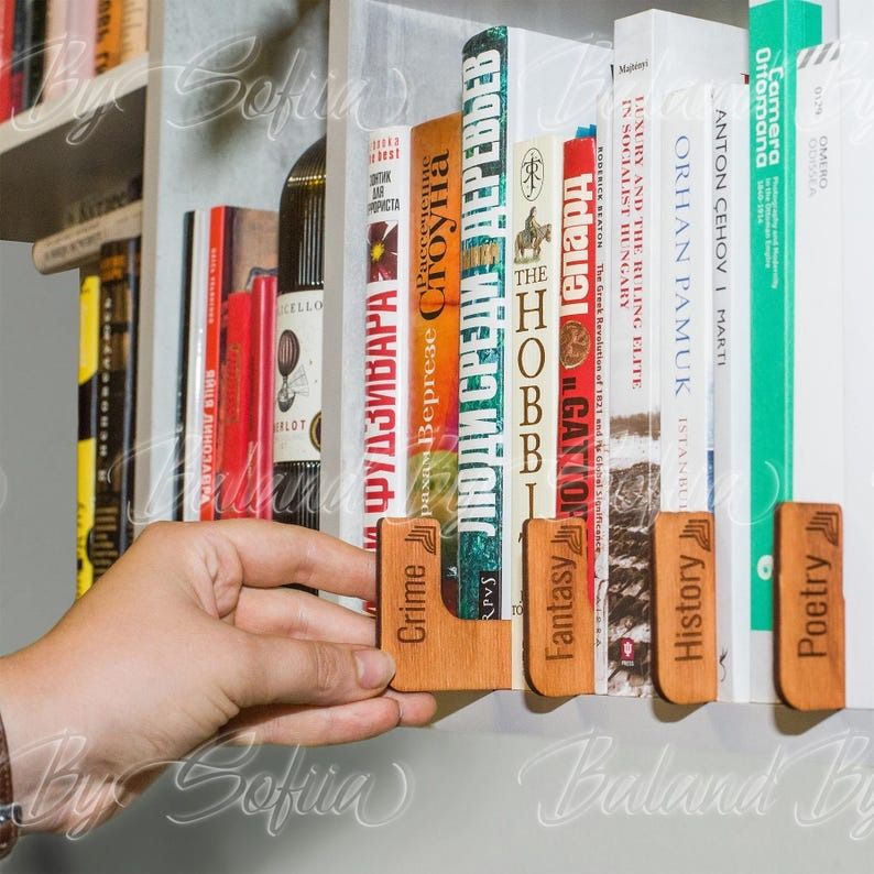 wooden bookshelf dividers with the names on genres on them