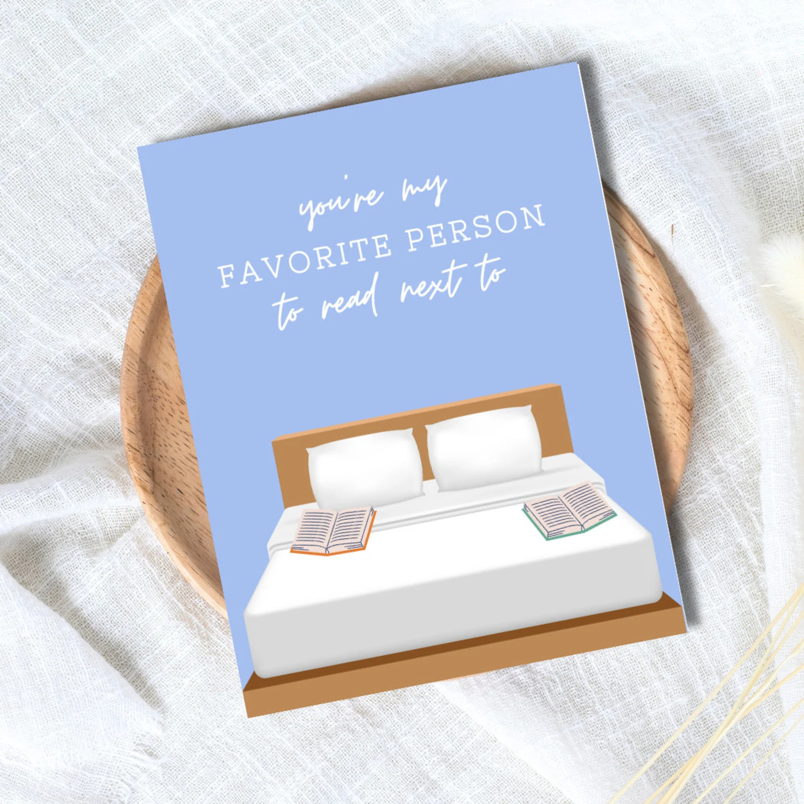 image of a birthday card with a bed and two open books on it. Above the bed are the words "you're my favorite person to read next to."