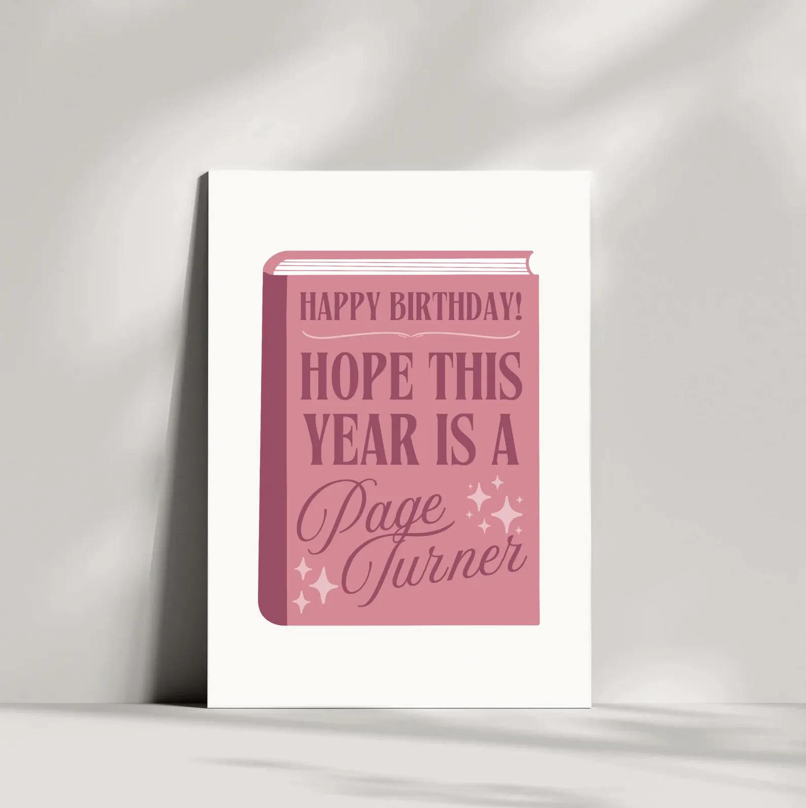 image of a card with a pink book on the front. it says "happy birthday! hope this year is a page turner."