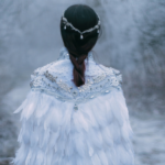 someone wearing a cloak of feathers walking in a forest