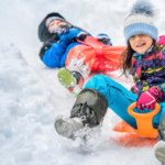 two kids sledding in the snow