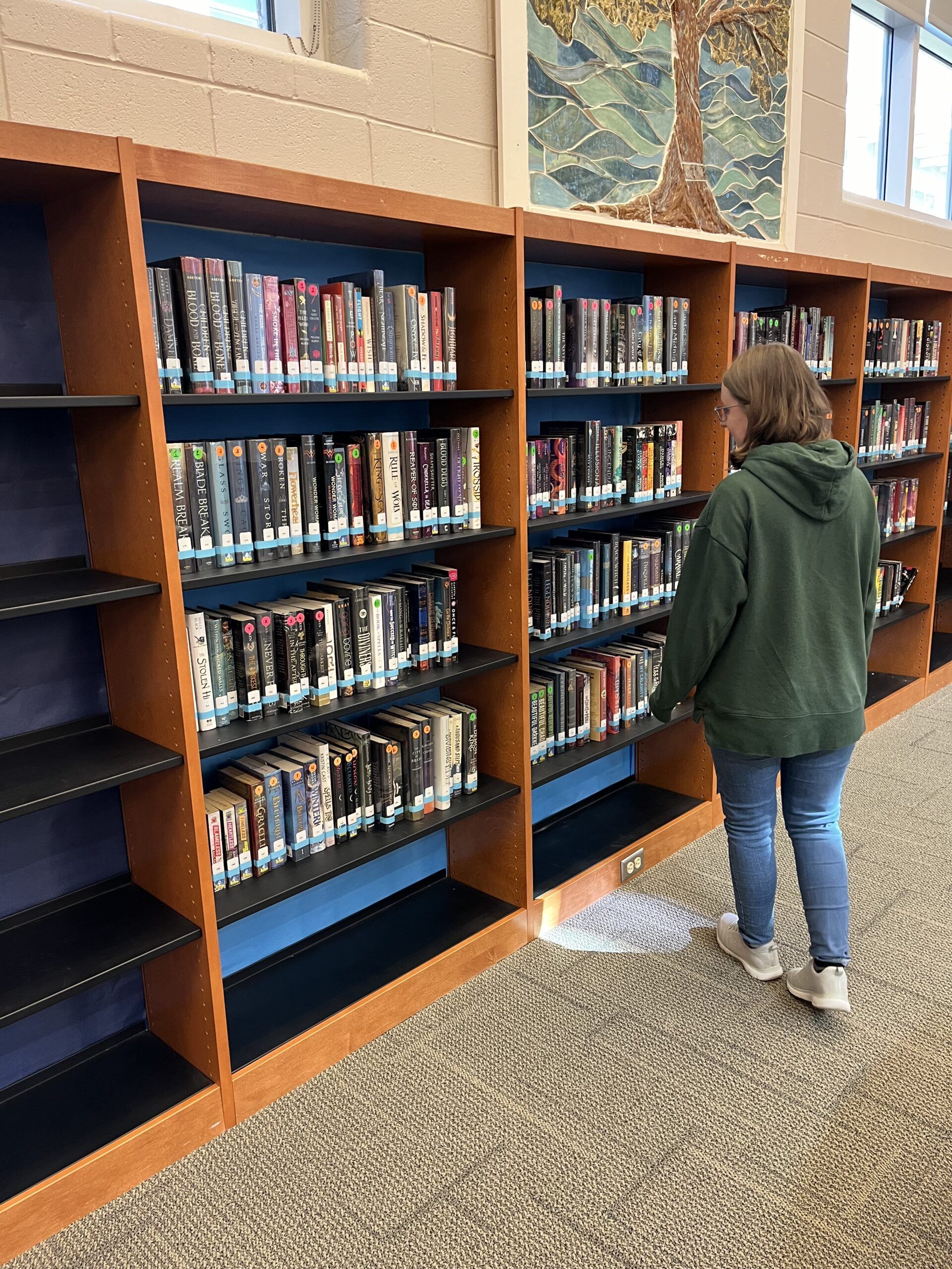 girl browsing full shelves with blue paper backing