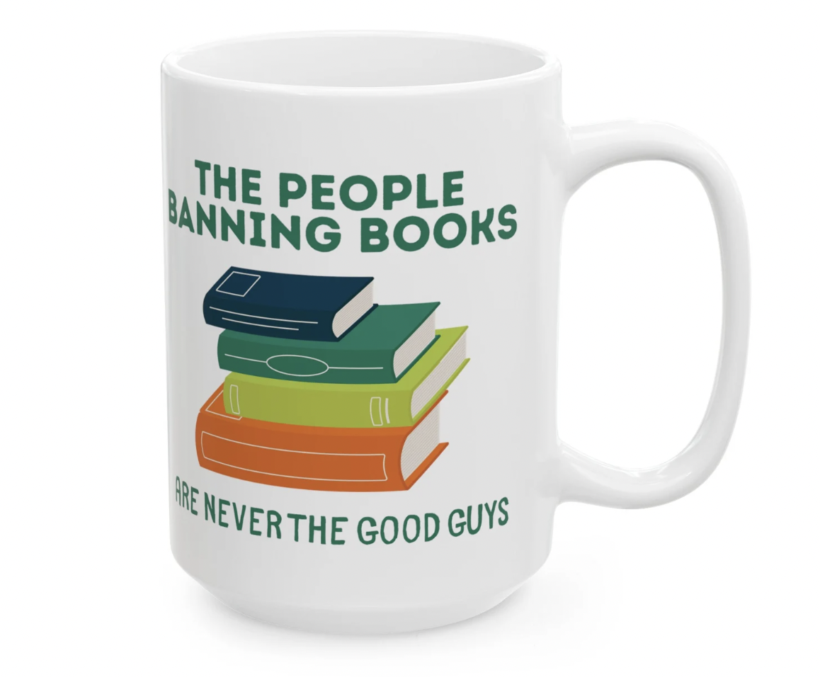 Photo of a white mug with an illustrated stack of books and the phrase "the people banning books are never the good guys"