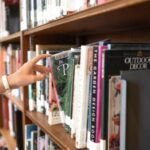 Image of hand pulling book from a library shelf