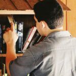 a light-medium skinned man looking at books in a Little Free Library