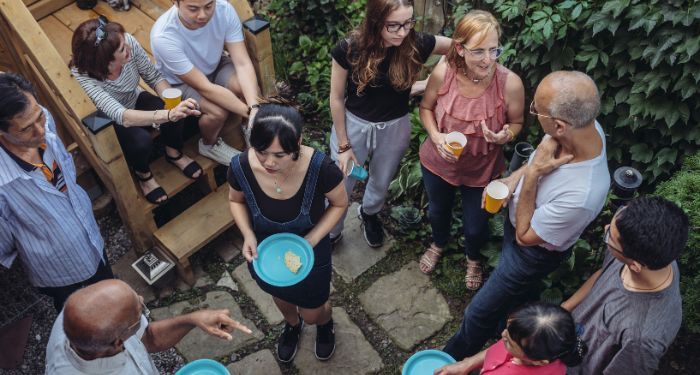 several people of different ages, genders, and races gathered in a backyard patio