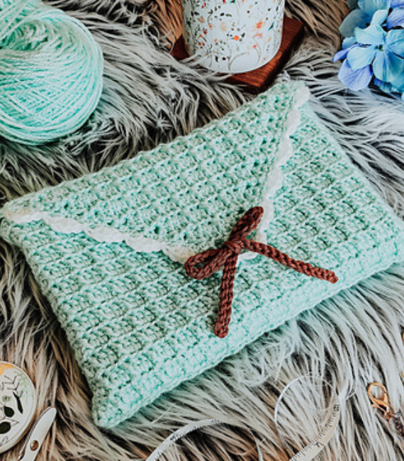 Pale blue crocheted book sleeve with with lacy edges and a brown bow in a very cottagecore style