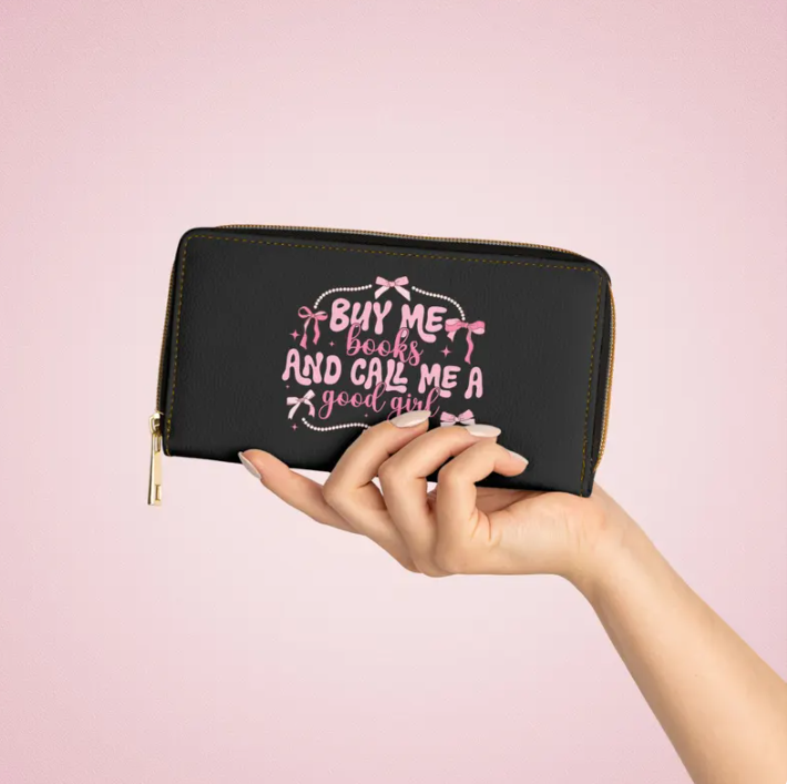 A hand holding a wallet that says "Buy me books and call me a good girl"